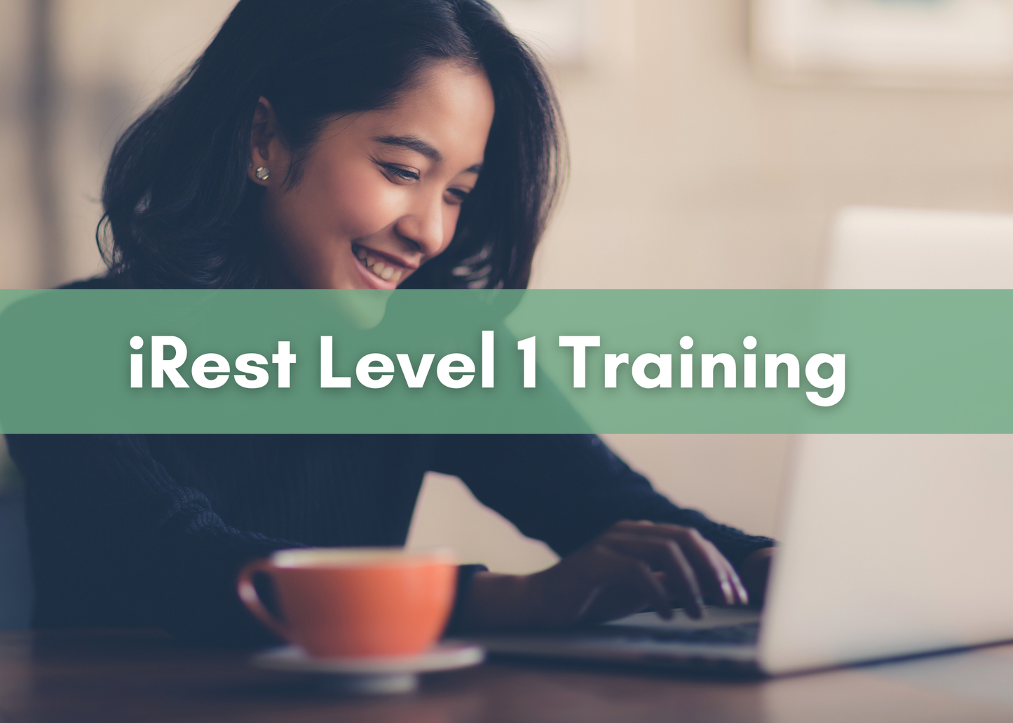 A smiling woman sits at a table typing on a laptop with an orange coffee cup beside her. A green banner across the image reads “iRest Level 1 Training” in bold white text.